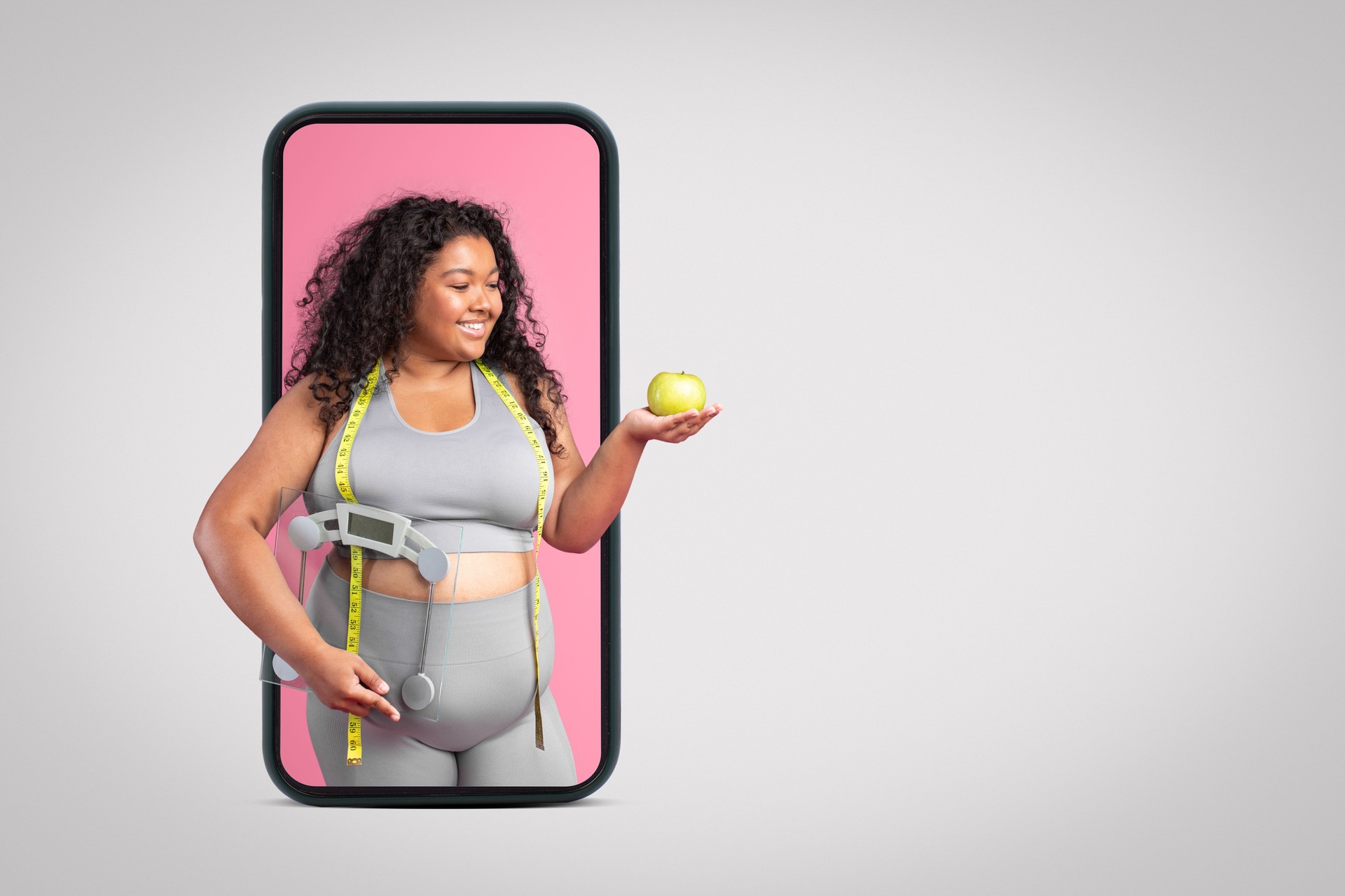 Black body positive woman in sportswear holding apple and scales, standing on big smartphone screen, banner, free space
